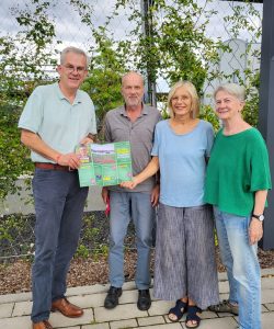 Bezirksbürgermeister Benedikt Spangenberg und die BV-Kandidat*innen Bodo Kensmann, Heike Deckert-Peaceman und Margret Wesseling mit einem Grünen Flyer